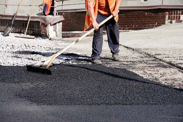 road workers lay asphalt in manual
