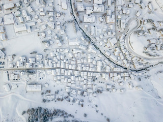 Aerial view of town with snow covered roofs. Village in Switzerland in winter with a lot of snow.