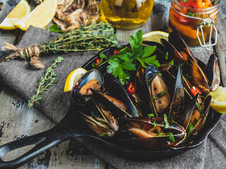 Cooked seafood  clams mussels in the iron pan portion with lemon and seasoning
