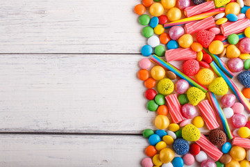 Fototapeta na wymiar mixed multicolored candies on white wooden background.