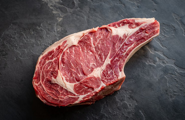 raw ribyey steak on stone background, prime meat on bone, top view © Andrey