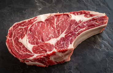 raw cowboy steak on stone background, prime rib eye on bone