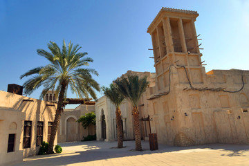 Traditional old house in Dubai with windcatcher and palm trees, Barasti or arish house, United Arab Emirates