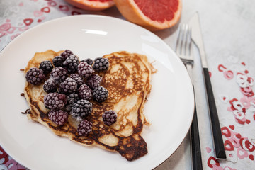 Delicious Hearts pancakes with blackberries on a white plate. Background with hearts and grapefruit. Romantic or healthy breakfast