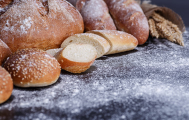 Bakery - gold rustic crusty loaves of bread and buns on black chalkboard background.
