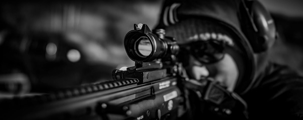 man looks through scope on rifle