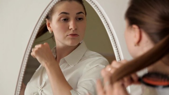 A young girl in the morning is going to work, getting dressed and doing her hair