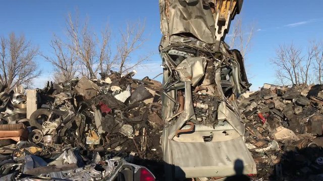 Powerful tool picks up car in junkyard and drops it dangerously close to camera thereafter.