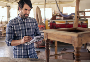 Craftsman creating a new chair design in his furniture workshop