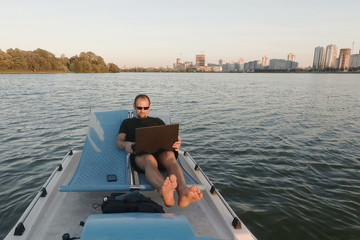 young freelancer works on the computer on a boat. Remote Business. passive earnings