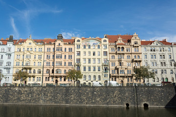 Row of old buildings on Vltava river waterfront,  in front of summer blue sky, in Prague, Czech Republic