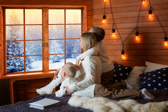 Mother And Children Rest In A Country House. Together They Lie On The Bed And Shoot Out The Window To The Snow Forest.