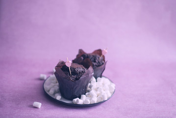 chocolate muffins with pink heart decor, chocolate muffins on a white plate, muffins on a pink background, muffins on a plate with marsh mallow (horizontally, pink toned).