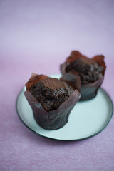 chocolate muffins on a white plate, muffins on a pink background (vertically).