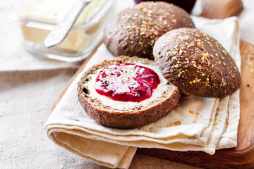 Homemade rye buns with linseeds, sesame and white poppy seeds served with butter and Jostaberry jam