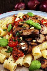 Penne pasta rigatoni in tomato sauce with mushrooms, tomatoes decorated with parsley and basil