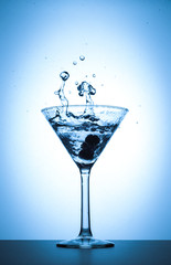 Cocktail martini glass splash on white and blue gradient background