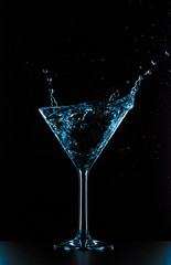 Cocktail martini glass splash on black background