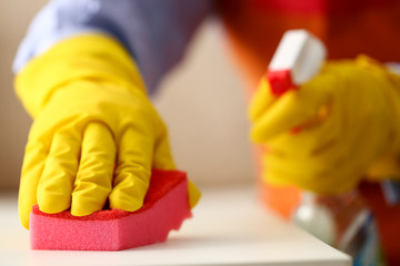 Arm in yellow latex protective glove wiping off dust