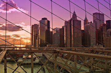 New York City at sunset seen through the cables of the Brooklyn Bridge
