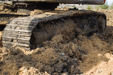 the tracks of a bulldozer, covered in mud, close-up