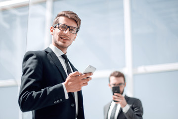 modern businessman with a smartphone on background office
