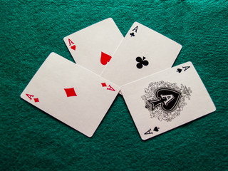 The four aces of a poker deck on a green mat