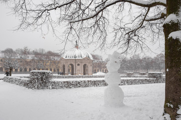 Schneemann in Münchens Hofgarten im Winter vor verschneiten Wahrzeichen
