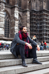 Stylish young man with beard sitting on the stairs
