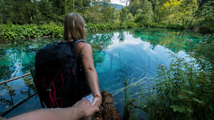 young woman with glasses holding hand while looking over lake in forest