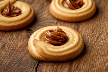 homemade butter cookies decorated with melted caramel on wooden background