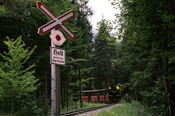 An old train crossing with an antique train in an open air museum.