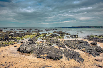 Dramatic landscape of Pembrokeshire coast, South Wales,Uk.Rocky beach during low tide and moody sky over horizon.Nature image with copy space.