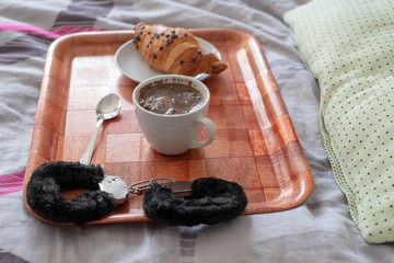 Coffee and sweet dessert on a bed linen. Erotic gadgets and underwear in the bedroom.