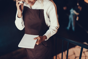 Glad woman with notepad speaking on telephone