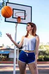Young woman enjoys on the basketball court with her ball