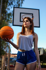 Young woman enjoys on the basketball court with her ball