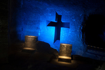 Blue cross with reclining chairs illuminated in blue tones and salt formations in its structure in the cathedral of salt in  Colombia, this cross is a tail that appears to be hollow by the wa