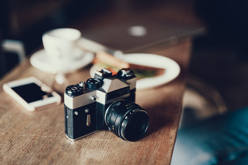 Fototapeta na wymiar Old fashioned photo camera lying on wooden table