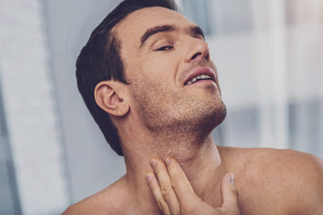 Obraz premium Positive handsome man applying a lotion