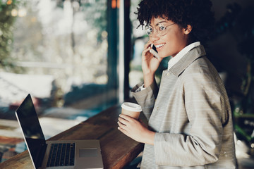 Woman standing inside cafe and speaking on telephone