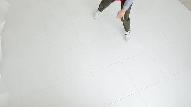 Professional male breakdancer performs unreal dance moves on the floor in a white studio