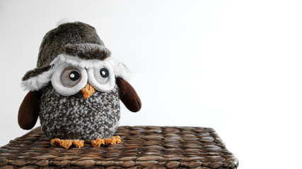 Obraz premium Toy owl sitting on a wicker box 