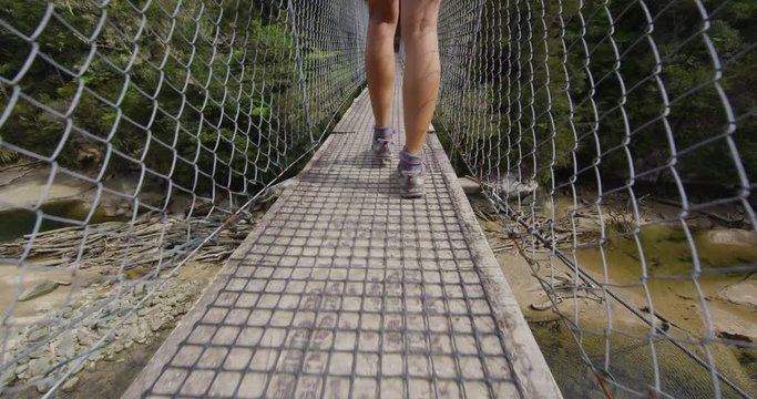 Hiking shoes close-up of hiking boots walking on bridge on hike track. Woman shoes on Abel Tasman Coast Track, one of the Great Walks and tramping tracks of New Zealand. SLOW MOTION.