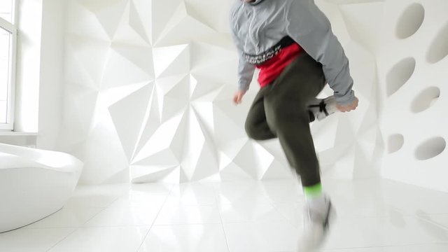 Professional male breakdancer performs unreal dance moves on the floor in a white studio