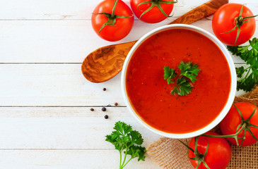 Homemade tomato soup. Above view, side border with copy space on a white wood background.