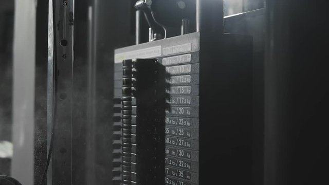 Weight falling in block machine and cloud of powder raising in dark gym in slo-mo.