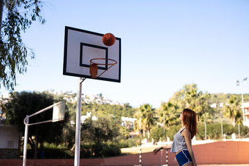 Young woman enjoys on the basketball court with her ball