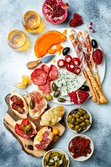 Fototapeten Appetizers table with antipasti snacks and wine in glasses. Brushetta or authentic traditional spanish tapas set, cheese and meat platter over grey concrete background. Top view © sveta_zarzamora
