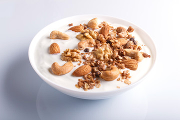 White plate with greek yogurt, granola, almond, cashew, walnuts isolated on white background.